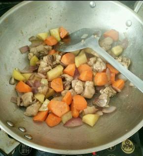 待鸡腿肉变色后加入胡萝卜和土豆翻炒片刻，然后加入适量开水，煮到胡萝卜和土豆熟透。