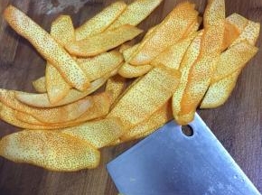 再用刀把橙皮白色的部分削干净。（一定要把白色的部分彻底清理干净哦，要不然做出来的糖会发苦。）