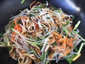 放入绿豆芽、香干丝、韭菜、鸡蛋饼丝，迅速翻拌。