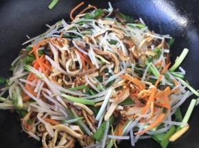 放入绿豆芽、香干丝、韭菜、鸡蛋饼丝，迅速翻拌。