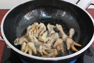 用炒锅热锅，到入适量的油，油温160度左右，倒入鸡爪炸至金黄色；千万要记得盖上盖子，油会溅出来。