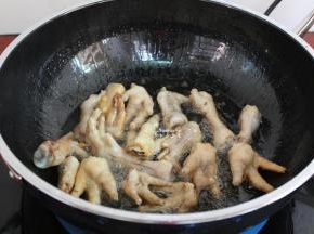 用炒锅热锅，到入适量的油，油温160度左右，倒入鸡爪炸至金黄色；千万要记得盖上盖子，油会溅出来。