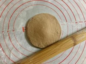 取其中一小份可可面团，搓圆按扁，擀成圆形。