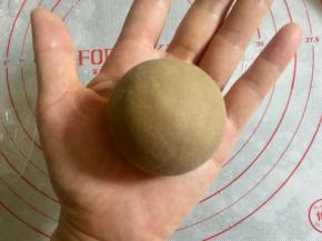 用虎口法把面皮包住奶黄馅，收圆，收口向下放。