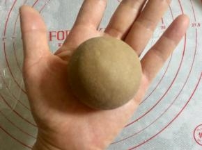 用虎口法把面皮包住奶黄馅，收圆，收口向下放。