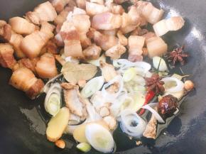 把五花肉扒到锅的一边，用锅里的底油煸炒葱姜、八角、草果、山奈、肉蔻、干辣椒，然后将五花肉和佐料翻炒在一起。