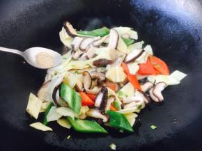 放入青红椒、冬笋、香菇、少许的白胡椒粉迅速翻炒。
