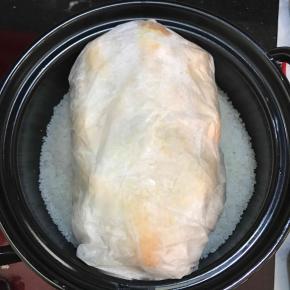 将炒好的海盐取出三分之二，另外的三分之一平铺在砂锅中，放入包裹好的鸡。