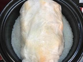 将炒好的海盐取出三分之二，另外的三分之一平铺在砂锅中，放入包裹好的鸡。