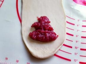 取一块松弛好的面团，用擀面杖擀成长舌状。
再放上自制草莓酱。(也可以把草莓酱平铺摊平，和面团一起擀成长舌状，根据个人喜欢来。)