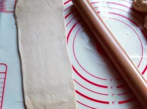 取一块松弛好的面团，用擀面杖擀成长舌状。