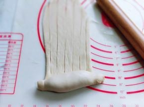 再长舌状面皮的另一端从下往上卷起来，卷到一半时停下来，再用水果刀切出条状，请看图。