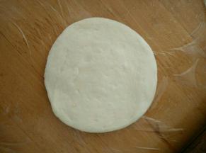 然后把面团竖起来，再用擀面杖擀成薄饼。两面都沾满芝麻。