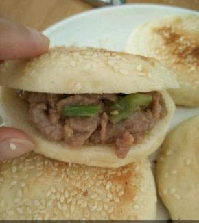 取个烧饼，用刀切开，不要切断。把牛肉塞进去。