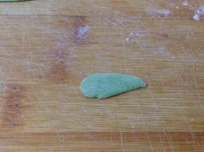 取少许绿色面团搓成水滴形压扁