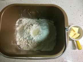 将黄油以外所有的原料放入面包桶，先放水，糖和盐对角的位置放入，再放入高粉、低粉和奶粉，铺满水面，然后在面粉顶部掏一个洞，把酵母倒进去。