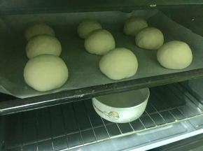 把豆沙包放进烤箱，同时放入一碗热水增加温度和湿度，进行二次发酵。
