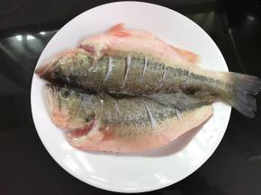 鲈鱼买回来后清洗干净，平铺。在鱼身上划几刀用料酒、盐和白胡椒粉腌制半小时。
