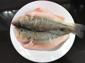 鲈鱼买回来后清洗干净，平铺。在鱼身上划几刀用料酒、盐和白胡椒粉腌制半小时。