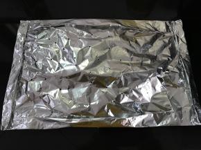 另取一张锡纸刷上油盖在鱼上包好。四周每条边都向内折起来，用牙签在锡纸上扎几个孔。