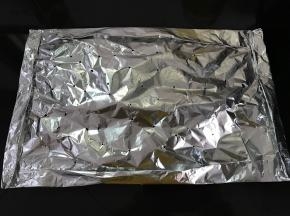 另取一张锡纸刷上油盖在鱼上包好。四周每条边都向内折起来，用牙签在锡纸上扎几个孔。