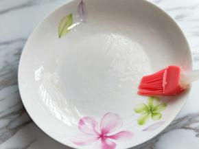 取一块深一点的盘子，刷上少许食用油，将面糊倒入盘中。