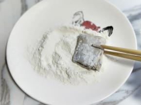 腌制好的带鱼，用筷子夹着沾满面粉。