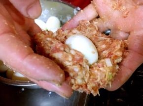 做龙眼丸子的第二步是塑形。 用手抓起一团约有150g的肉馅，把它捏成直径大约8或9厘米的小圆饼，在小圆饼的中间轻轻的按压一个浅浅的凹窝，放入一只鸡蛋。