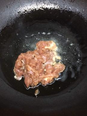 锅里倒入适量的油烧热后，将肉放入划开，炒到变色
