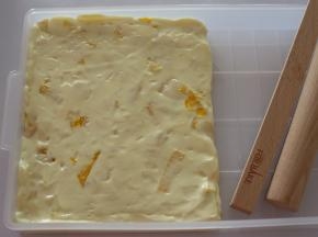 折叠之后的牛轧糖更好吃哦，折叠好之后将它们放在牛轧糖盘中，大致按压之后，用擀面杖将它们擀平。