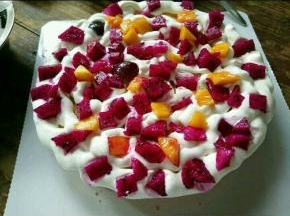 取一片蛋糕放在蛋糕纸托上，在上面抹一层奶油，均匀的铺上水果，然后再抹一层奶油。