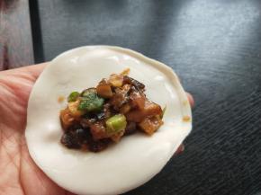 用清水在饺子皮边缘抹一圈，放肉馅，七分满。