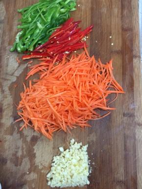 青椒，红尖椒清洗干净以后切成丝，胡萝卜削皮洗净切成丝，蒜瓣剥皮拍碎切成末备用。