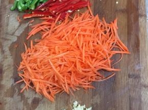 青椒，红尖椒清洗干净以后切成丝，胡萝卜削皮洗净切成丝，蒜瓣剥皮拍碎切成末备用。