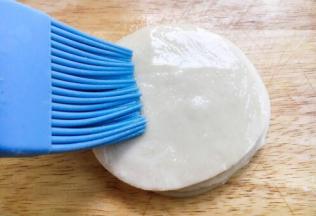 取一张饺子皮，在表面刷上薄薄一层的油。