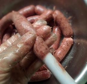 一只手摇一只手拉一下这样做出来的肠比较均匀，注意灌肠的时候不能罐太满也不能罐太少，用手捏过去能捏一半左右就可以扎绳子了，这样是为了扎绳子的时候不爆开