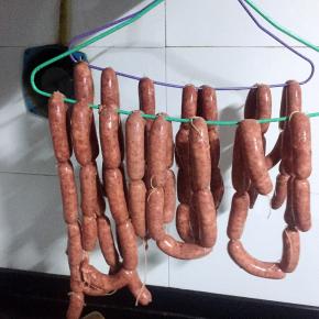 扎好绳子以后挂在阴凉通风的地方晾晒，直到表皮干爽即可，我是挂在厨房的通风口挂了一晚上，天气比较暖和或者家里有暖气的不建议长时间晾晒会变坏的，可以对着电风扇吹两个小时至表皮干爽，晾晒完毕用牙签在脆皮肠上扎几个小孔是为了防止煮的时候炸开