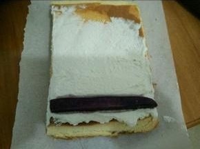 淡奶油加入糖粉打到九分发。取一半蛋糕抹上奶油，再放上紫薯，卷起来。用油纸包好放冰箱冷藏一个小时。