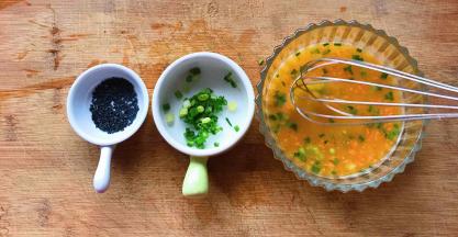 把加入胡萝卜丁和葱花的蛋液再搅拌均匀，准备好黑芝麻，剩余的葱花装容器里备用