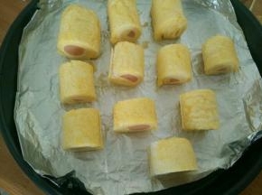 时间到，撕去保鲜膜，把吐司卷分成两个还是三个都可以。摆在披萨盘里，在表面刷蛋液。