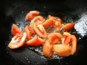 西红柿去皮切滚刀块状，锅内加适量植物油和猪油，下西红柿大火翻炒一分钟。