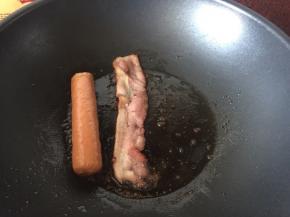 锅里热油后放入热狗和培根煎香