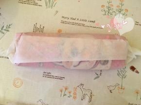 用擀面杖卷住油纸，顺势往上推。卷起来，两边跟拧糖一样拧起来。放入冰箱冷藏半小时后再切块食用。