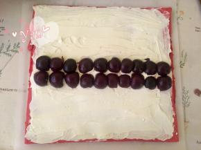 蛋糕片盖上油纸，把油纸和蛋糕片翻过来，切去尾端，抹上打发的淡奶油，中间堆高点，再放上去核的车厘子；