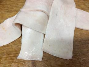 买回来的肉皮，用水洗干净，然后用刀将两边的油刮掉，在把肉皮切成几个长条