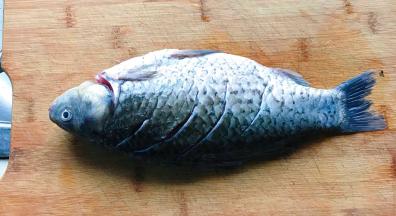 把鱼放在案板上，两面各切三刀，最好能横着切