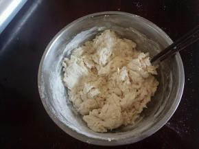把面团用料全部放入碗中混合，加入温水，用筷子挑成絮状。