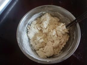 把面团用料全部放入碗中混合，加入温水，用筷子挑成絮状。