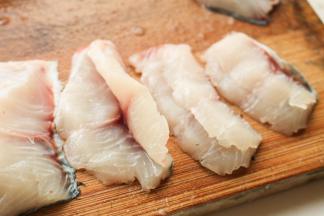 一条草鱼西安鱼骨处片开成两片，中间的鱼骨切段待用。再来处理鱼肉片，鱼肉斜着切片，第一刀不切断，第二刀再切段，这样就是蝴蝶片，如图所示。不要切的太薄，太薄了一煮就容易碎成渣。