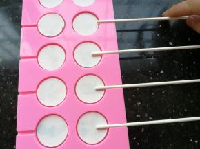 再放入棒棒糖棍子。重复步骤2、3、4、5继续熬煮另外250克珊瑚糖，同样也是加入25ml水煮，煮好后倒入已经放好图案的棒棒糖模具中至满模即可。